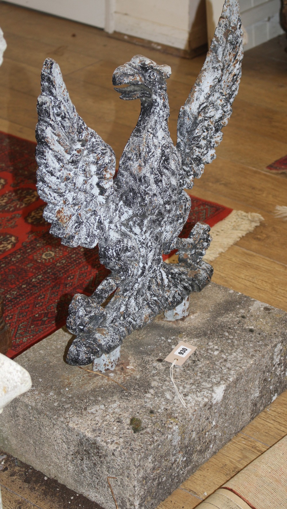 A cast iron spread eagle garden ornament with stone plinth base, W.52cm H.75cm